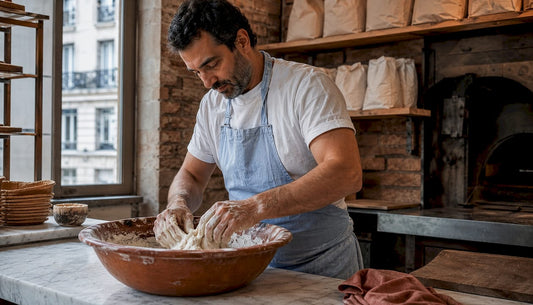 Un artisan boulanger façonne à la main sa pâte au levain naturel dans son fournil.