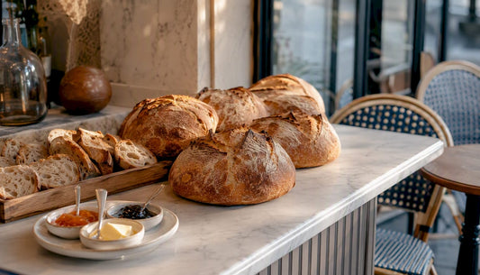 Une sélection de pains au levain artisanaux disposés sur une table en bois, pour éveiller les papilles des amateurs de boulangerie.