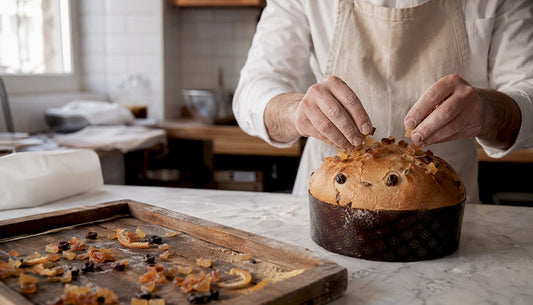 Un boulanger dépose délicatement un panettone tout juste sorti du four sur une grille afin de le laisser refroidir.