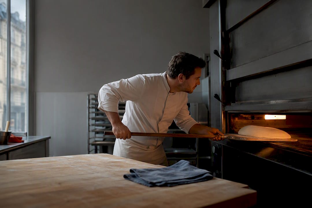 Boulanger plaçant une pâte dans le four à l'aube