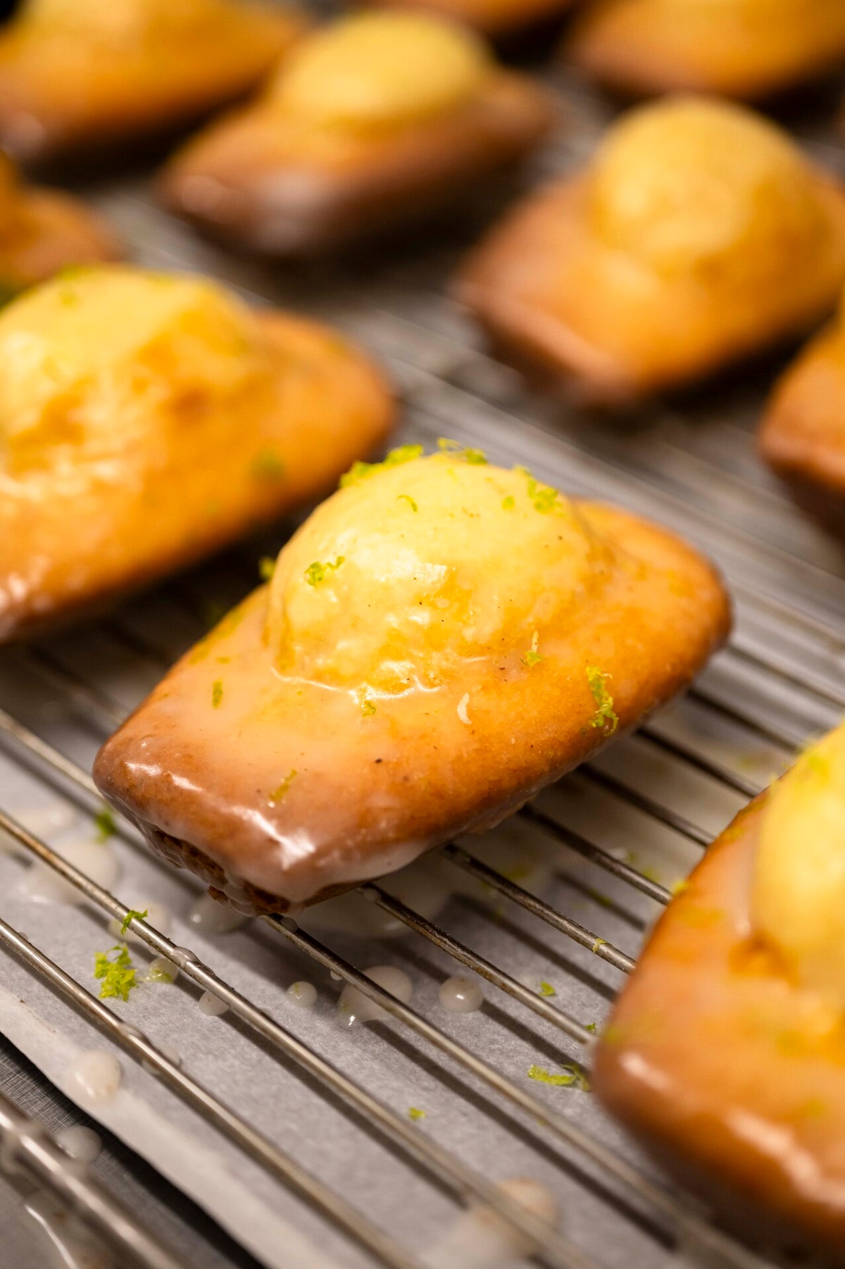 Madeleines fleur d'oranger Christophe Louie dressées sur assiette blanche avec branche d'oranger